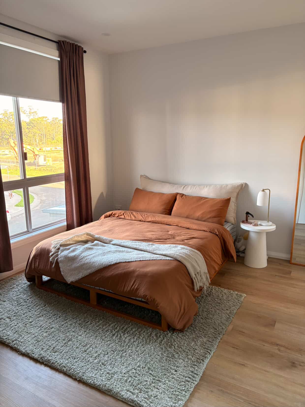 Stone linen bedhead cushion in modern bedroom with terracotta bedding and shag rug