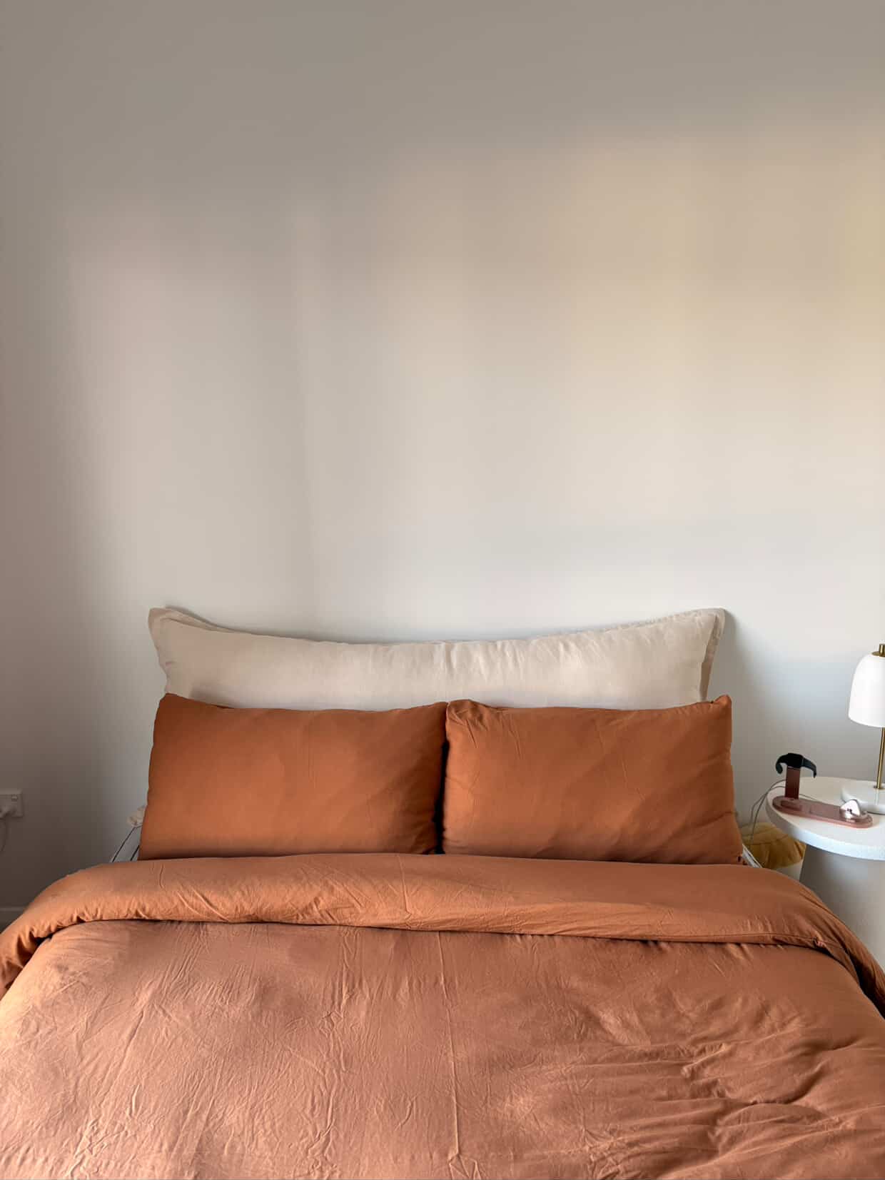 Stone linen bedhead cushion front view with terracotta pillows