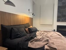 Custom black bouclé bedhead cushion on bed with evening lighting