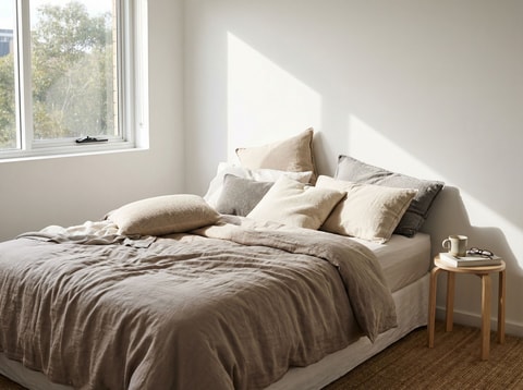Pillows fallen over against bare wall
