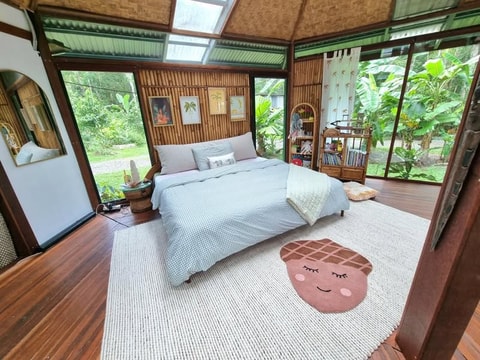 Wide view of tropical bedroom with bouclé bedhead cushion
