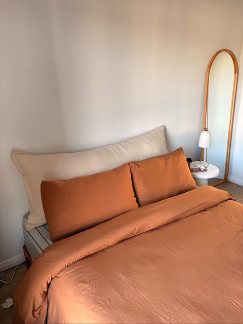 Stone linen bedhead cushion with terracotta bedding and arched mirror